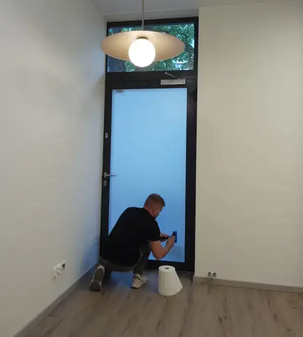 Etap montażu folii mrożonej na drzwiach w lokalu w Katowicach