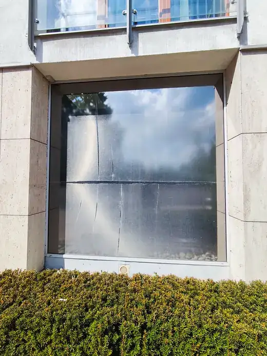 Zużyta stara folia przeciwsłoneczna na dużej szybie gabinetu dentystycznego w Krakowie przed demontażem